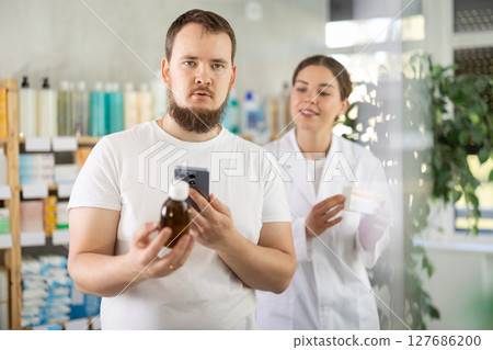 Man buyer scans syrup qr code with woman pharmacist 127686200