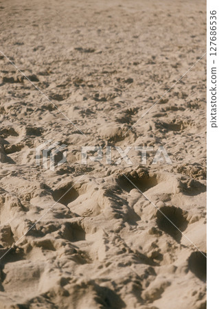chain of footprints in the sand. The footprints of human shoes are arranged in row and very close. 127686536