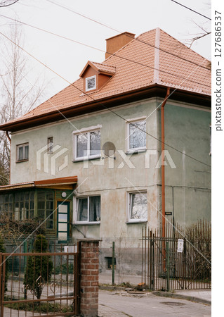 old brown building with a balcony. The building is surrounded by a fence.  127686537