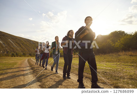 Young tourists with large backpacks hiking in nature walking in a row outdoors. 127686899