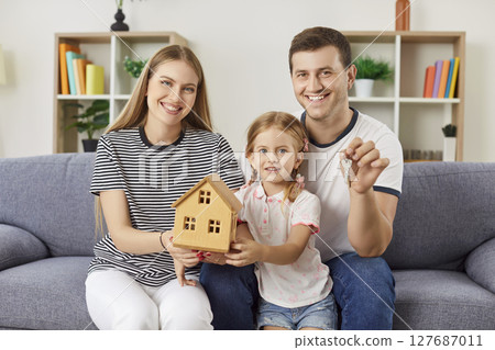 Happy family holding tiny toy house in hands, young married couple buying new house, apartment Happy family holding tiny toy house in hands, young married couple buying new house, apartment 127687011