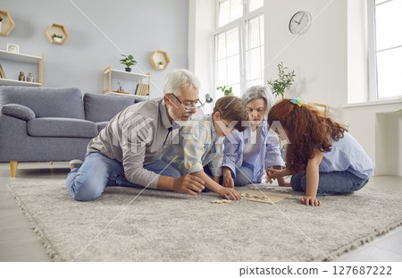 Happy Grandparents And Grandchildren Playing Puzzle Together At Home 127687222