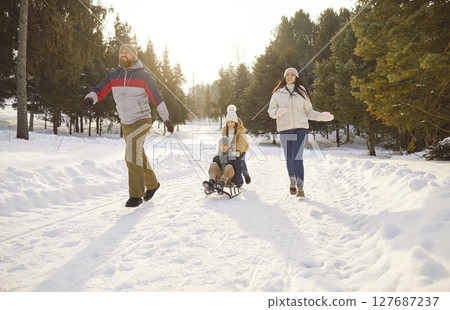 Full length portrait of happy joyful family having fun with their children walking in winter park. 127687237