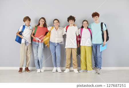 Happy preteen school children in colorful clothes hugging and smiling together, making group photo. 127687251