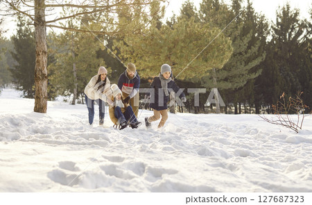 Happy family with kids having fun in winter park sledding together in nature 127687323