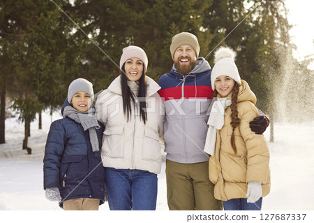 Happy family with kids standing in winter park together looking at camera. 127687337