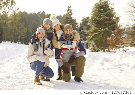 Happy family with kids standing in winter park together hugging and looking at camera. Happy family with kids standing in winter park together hugging and looking at camera. 127687361