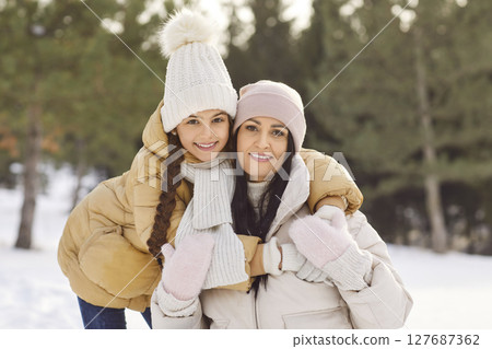 Winter snowy outdoor family portrait, mother, daughter on holiday wearing warm outfit Winter snowy outdoor family portrait, mother, daughter on holiday wearing warm outfit 127687362