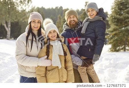 Happy family with kids standing in winter park together looking cheerful at camera. Happy family with kids standing in winter park together looking cheerful at camera. 127687371