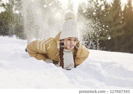 Happy smiling little child girl riding on a snow slide in snowy winter park. Happy smiling little child girl riding on a snow slide in snowy winter park. 127687393