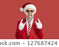 Man in red suit, Santa hat and sunglasses doing rock gesture and sticking tongue out 127687424