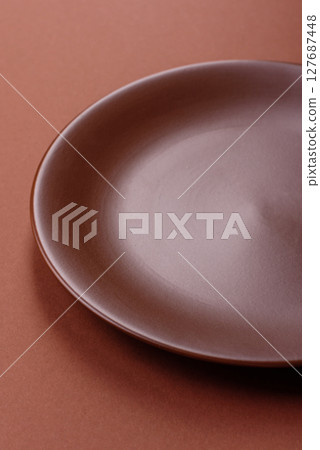 Empty ceramic plate on a monochrome brown background Empty ceramic plate on a monochrome brown background 127687448