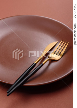 Empty ceramic plate on a monochrome brown background Empty ceramic plate on a monochrome brown background 127687452