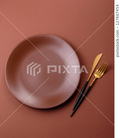 Empty ceramic plate on a monochrome brown background Empty ceramic plate on a monochrome brown background 127687454