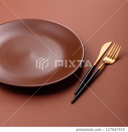 Empty ceramic plate on a monochrome brown background 127687455