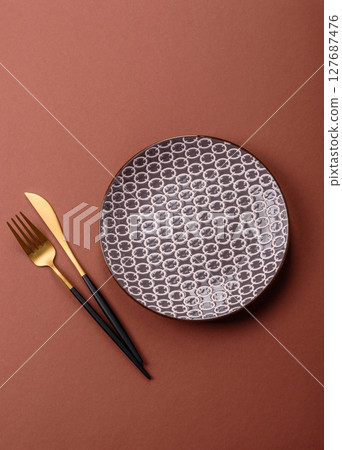 Empty ceramic plate on a monochrome brown background Empty ceramic plate on a monochrome brown background 127687476