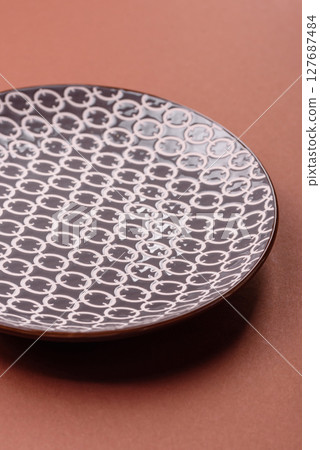 Empty ceramic plate on a monochrome brown background Empty ceramic plate on a monochrome brown background 127687484