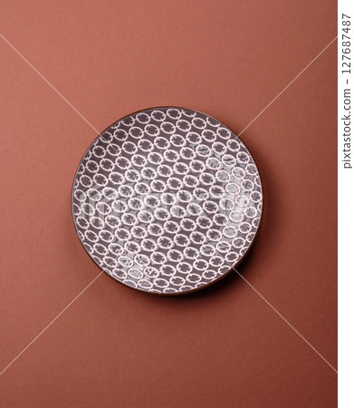 Empty ceramic plate on a monochrome brown background 127687487