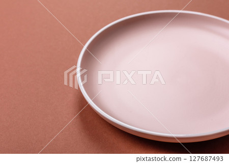 Empty ceramic plate on a monochrome brown background Empty ceramic plate on a monochrome brown background 127687493