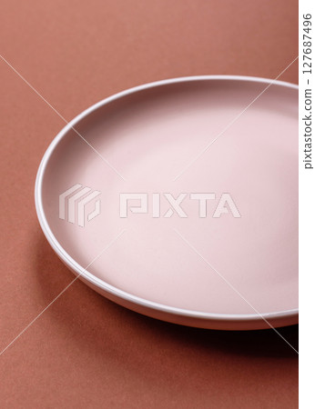 Empty ceramic plate on a monochrome brown background 127687496
