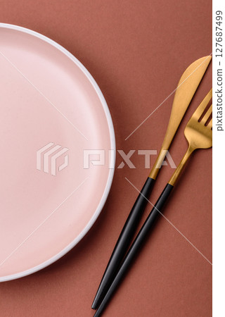 Empty ceramic plate on a monochrome brown background Empty ceramic plate on a monochrome brown background 127687499