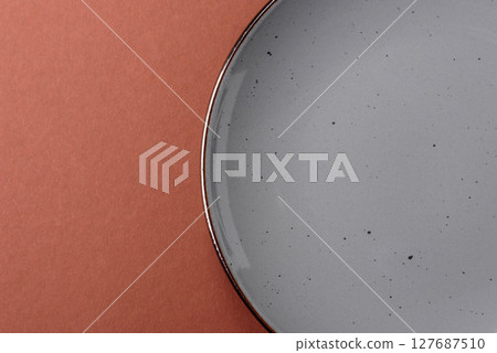 Empty ceramic plate on a monochrome brown background 127687510