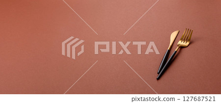 Knife and fork, cutlery on a brown dining table Knife and fork, cutlery on a brown dining table 127687521