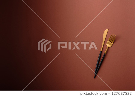 Knife and fork, cutlery on a brown dining table Knife and fork, cutlery on a brown dining table 127687522
