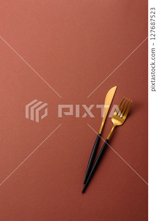 Knife and fork, cutlery on a brown dining table Knife and fork, cutlery on a brown dining table 127687523