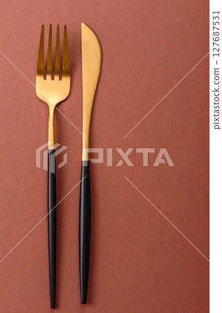 Knife and fork, cutlery on a brown dining table Knife and fork, cutlery on a brown dining table 127687531