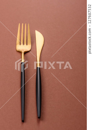 Knife and fork, cutlery on a brown dining table 127687532