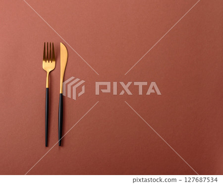 Knife and fork, cutlery on a brown dining table 127687534