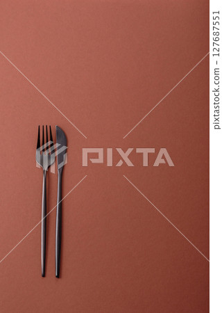 Knife and fork, cutlery on a brown dining table Knife and fork, cutlery on a brown dining table 127687551