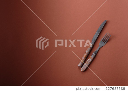 Knife and fork, cutlery on a brown dining table 127687586
