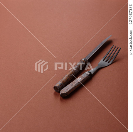 Knife and fork, cutlery on a brown dining table 127687588