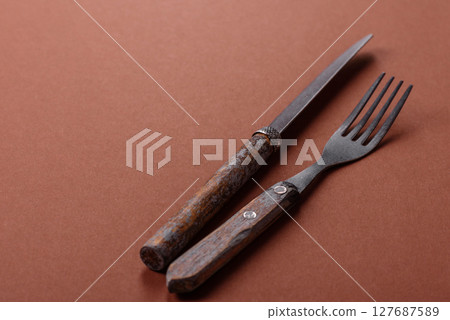 Knife and fork, cutlery on a brown dining table 127687589