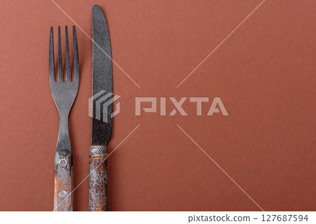 Knife and fork, cutlery on a brown dining table 127687594