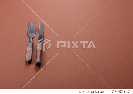 Knife and fork, cutlery on a brown dining table 127687597