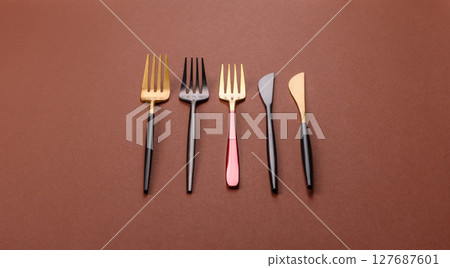 Knife and fork, cutlery on a brown dining table Knife and fork, cutlery on a brown dining table 127687601