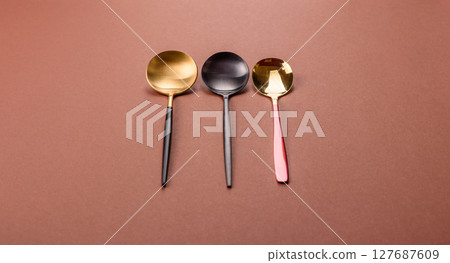 Empty metal spoon on a monochrome brown background 127687609