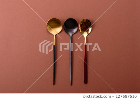 Empty metal spoon on a monochrome brown background 127687610