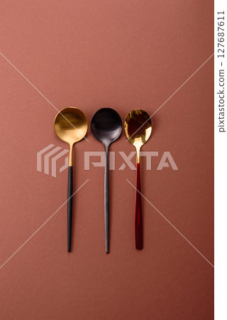 Empty metal spoon on a monochrome brown background 127687611