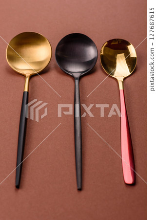 Empty metal spoon on a monochrome brown background 127687615