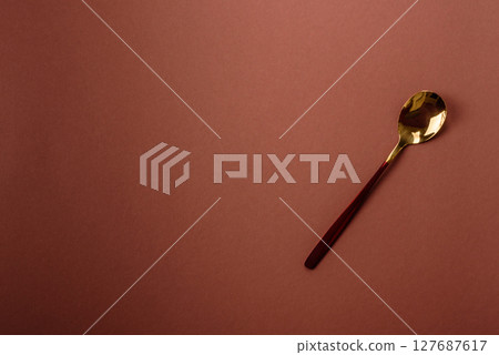 Empty metal spoon on a monochrome brown background 127687617