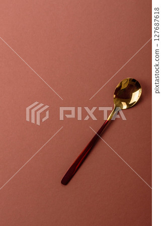 Empty metal spoon on a monochrome brown background 127687618
