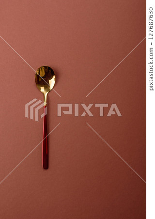 Empty metal spoon on a monochrome brown background Empty metal spoon on a monochrome brown background 127687630
