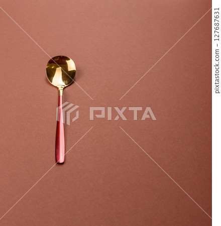 Empty metal spoon on a monochrome brown background Empty metal spoon on a monochrome brown background 127687631