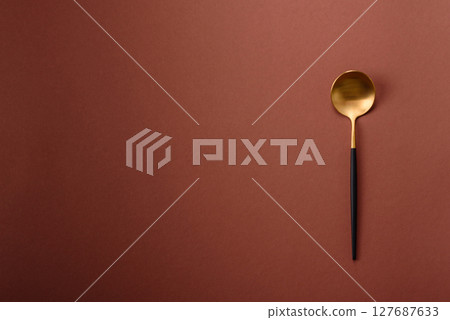 Empty metal spoon on a monochrome brown background Empty metal spoon on a monochrome brown background 127687633