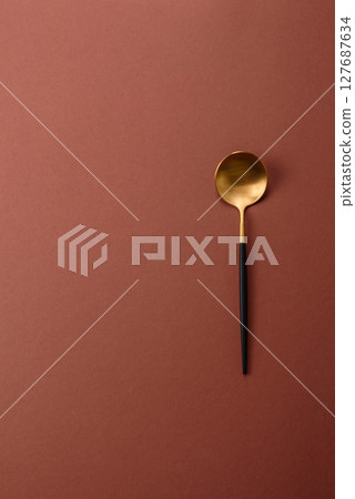 Empty metal spoon on a monochrome brown background Empty metal spoon on a monochrome brown background 127687634