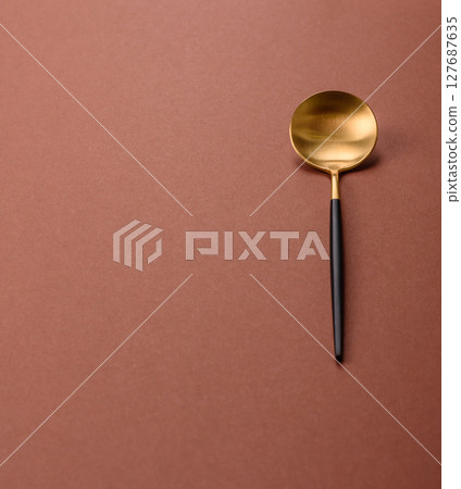 Empty metal spoon on a monochrome brown background Empty metal spoon on a monochrome brown background 127687635